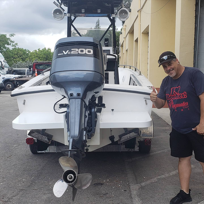 Man standing next to a Wellcraft 23ft boat, giving a thumbs up.